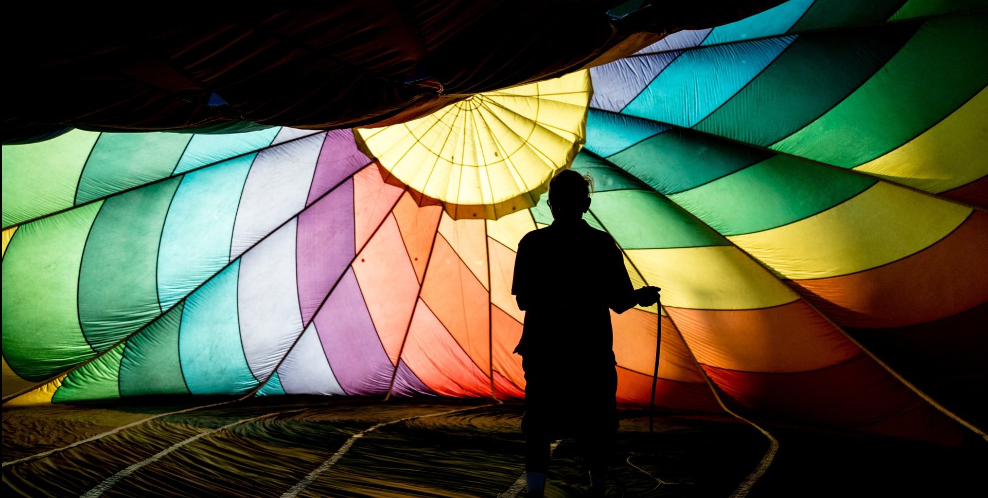 silhouette of a person outside a rainbow parachute